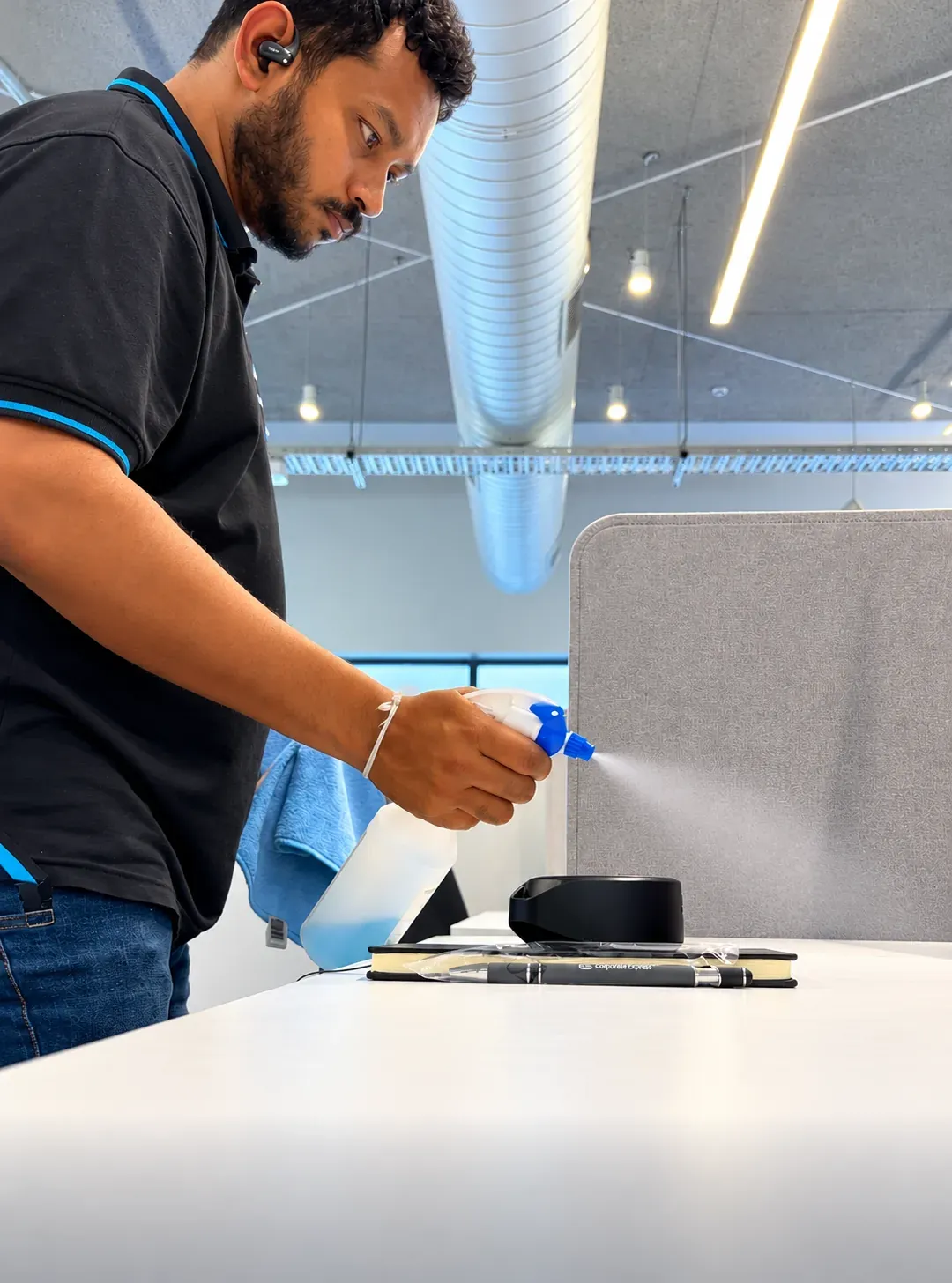 HNT team member spraying and wiping down an office desk