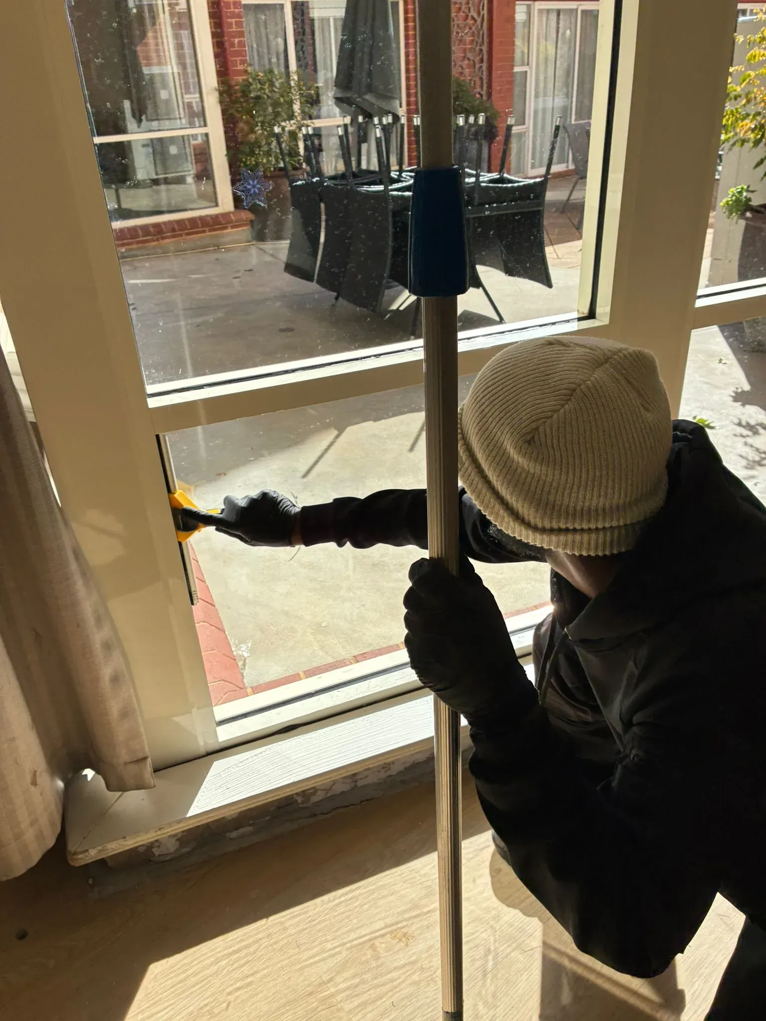 HNT team member cleaning a window with a pole
