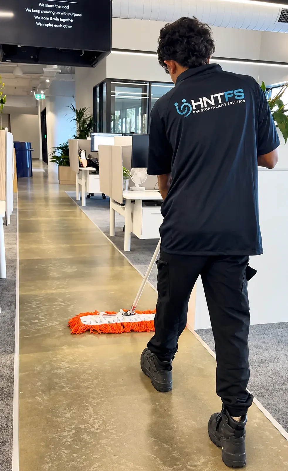 HNT team member dust mopping a corridor floor in an office
