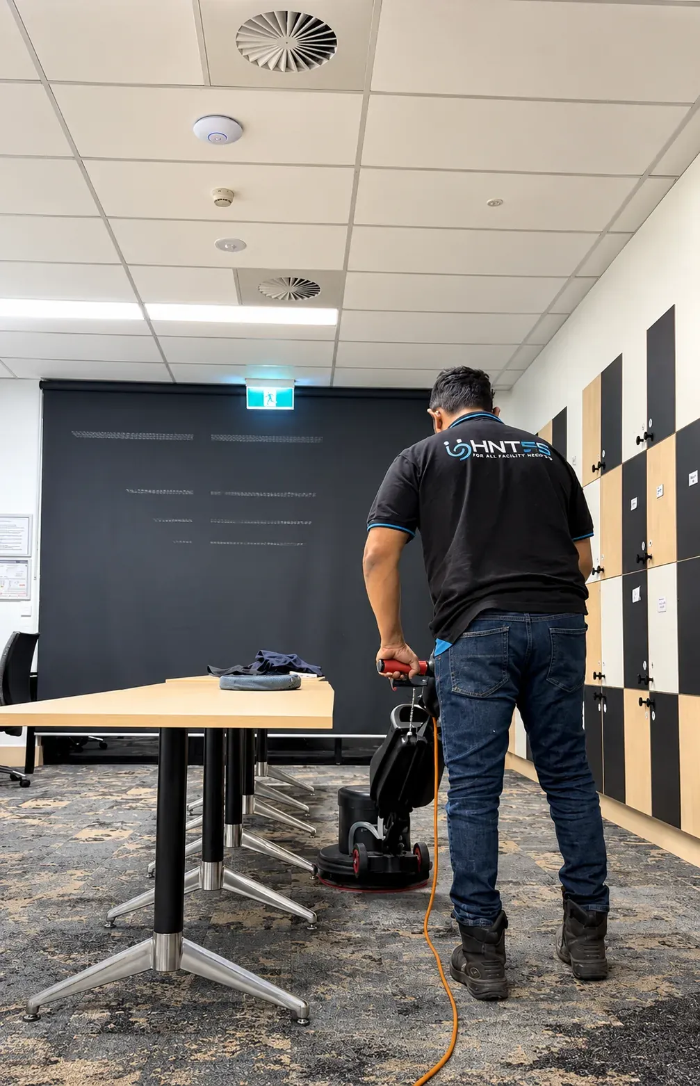 HNT team member operating a floor scrubber in an office meeting area