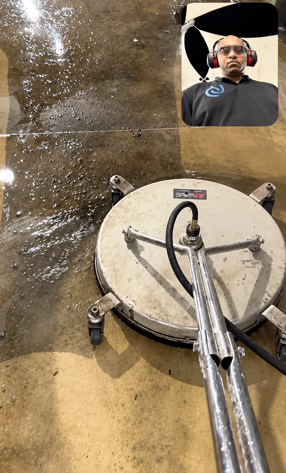 Overhead view of a rotary surface cleaner pressure washing a ground surface