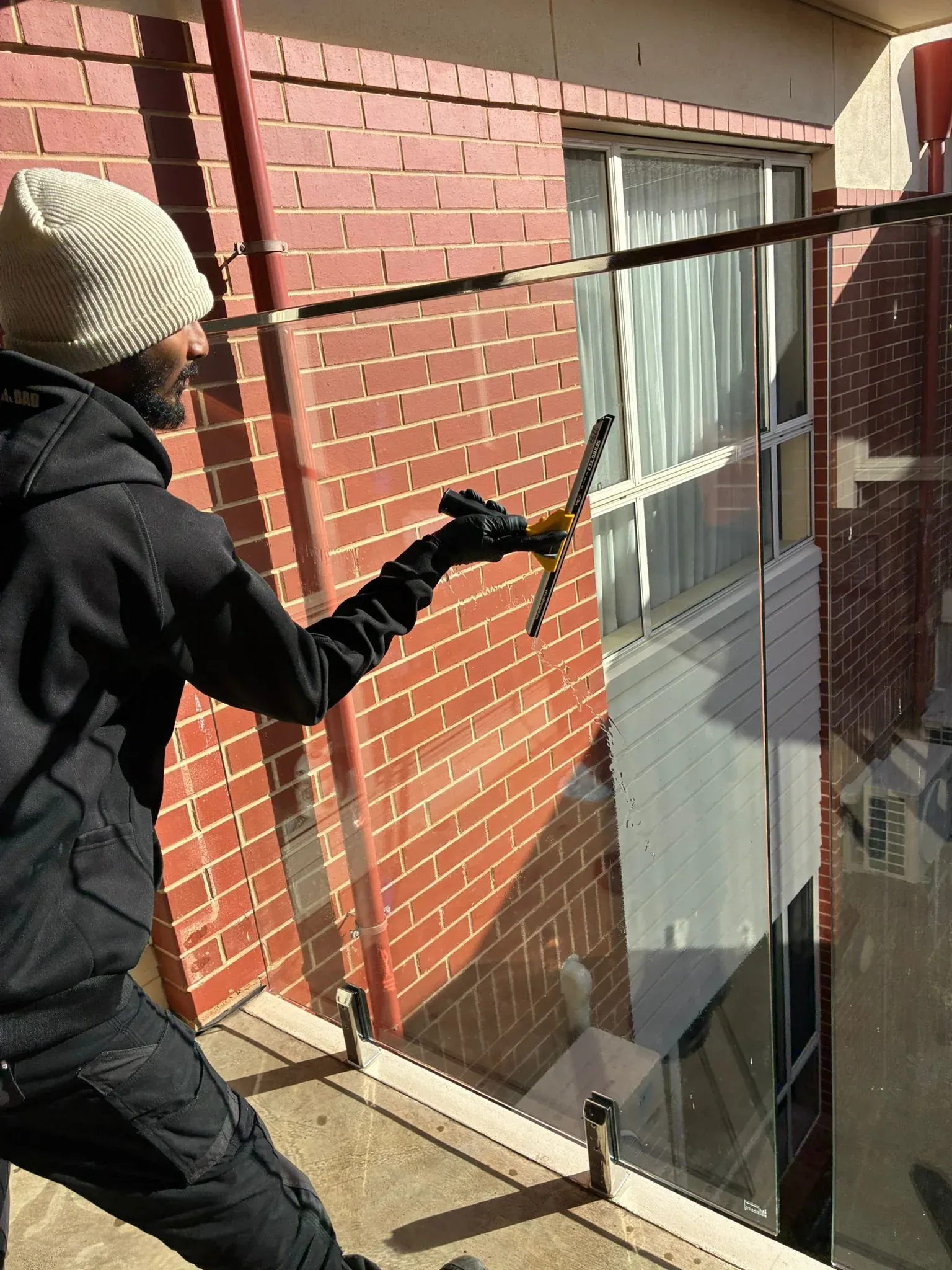 HNT team member pressure washing a brick wall beside a window
